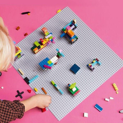 Criança a construir sobre a Lego Classic Placa de Construção Cinzenta