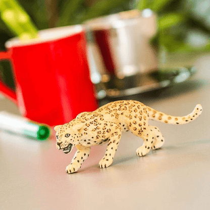 Figura de borracha Leopardo sobre uma mesa junto a uma chávena