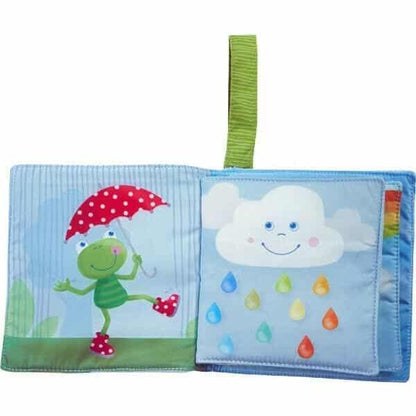 Livro de Tecido Arco-Íris aberto com sapo, guarda-chuva e nuvem