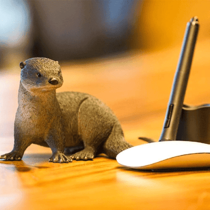 Figura de borracha Lontra numa mesa junto a um rato de computador