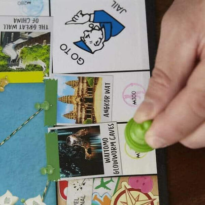 Mão a colocar um autocolante numa casa do tabuleiro Monopoly Viaja Pelo Mundo