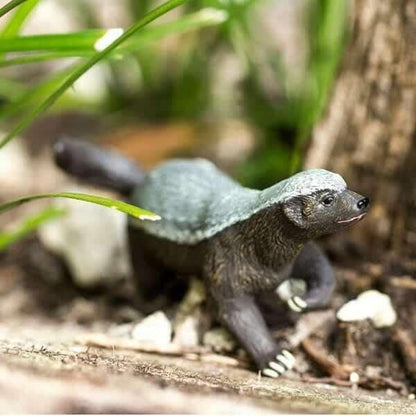 Figura de borracha Ratel num cenário natural entre ervas e pedras