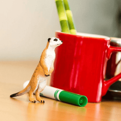 Figura de borracha Suricata junto a uma caneca vermelha