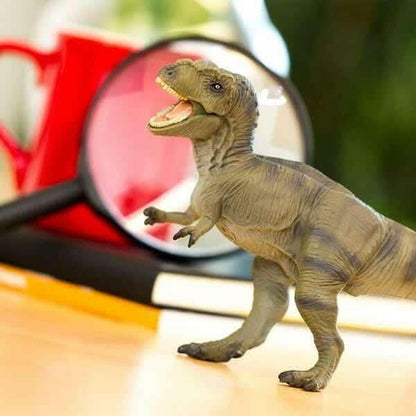 Figura de borracha Tyrannosaurus Rex numa mesa junto a uma lupa