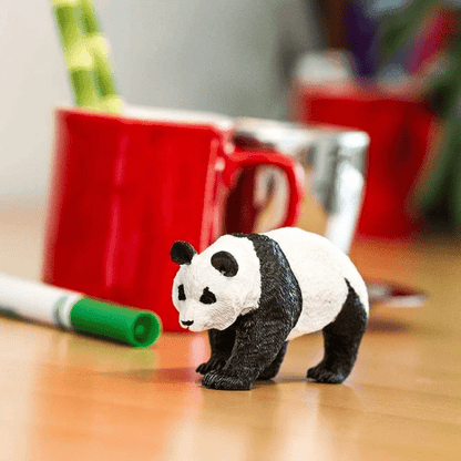 Figura de borracha Urso Panda numa mesa junto a uma caneca vermelha